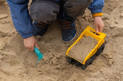 Thematic photo of a child playing with a remote-controlled CAT dump truck in a sandbox or playroom