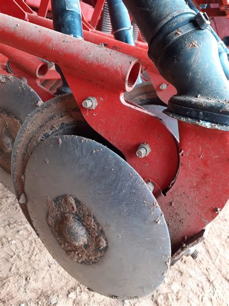 Thematic photo of the sowing unit of a corn planter with disc coulters and press wheels on a field