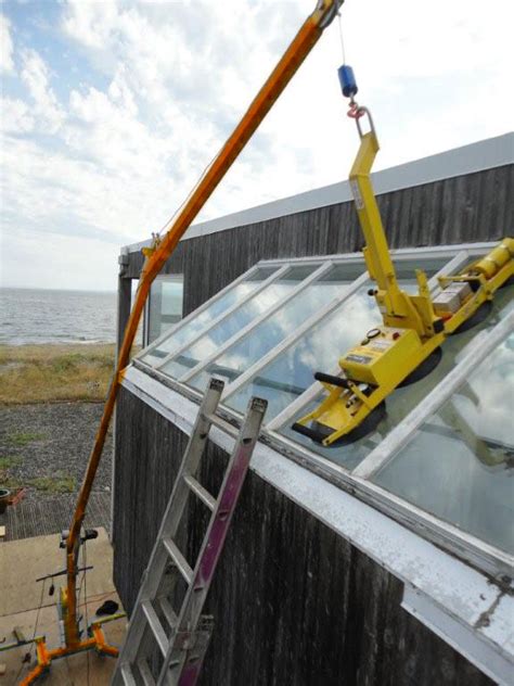 Photo of a mini crane with a glass manipulator lifting a large window