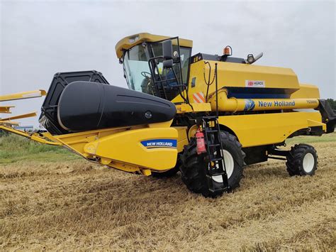Zdjęcie przedstawiające używany kombajn zbożowy New Holland TC 5070 na polu podczas żniw