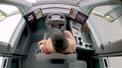 The interior of the Tesla Semi cabin, showing the central driver's seat and two large touchscreens on either side of the steering wheel.