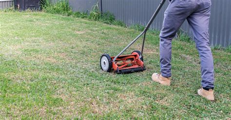 Thematic photo of a person pushing a hand mower on a small lawn