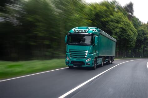 Ciężarówka z naczepą na drodze ekspresowej, prezentująca realia transportu drogowego