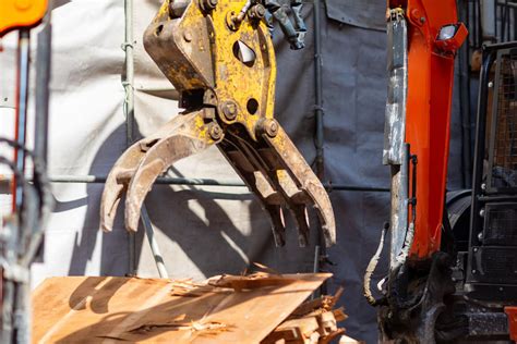 Zdjęcie przedstawiające różne rodzaje łyżek i osprzętu do koparko-ładowarki.