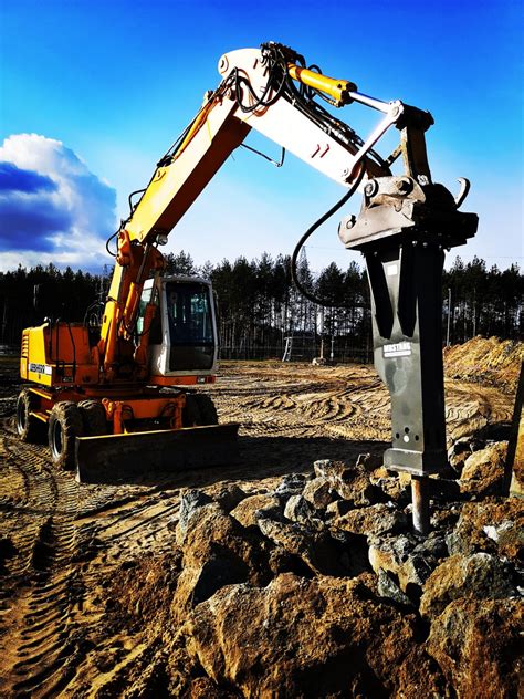 Zdjęcie koparki Komatsu PW180-7E0 pracującej z młotem wyburzeniowym