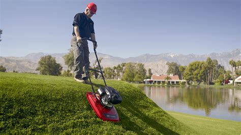 Thematic photo of a person mowing a lawn on a steep slope with a two-stroke mower