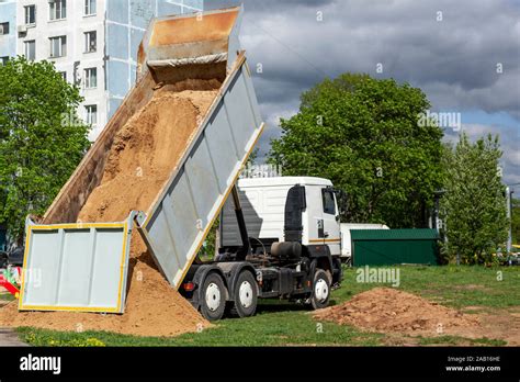 Thematic photo of a large dump truck unloading sand on a construction site