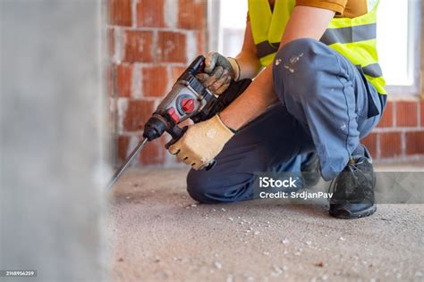 Thematic photo of a construction site with a worker operating a demolition hammer.