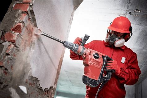 Thematic photo of a worker using a demolition hammer with all safety equipment.