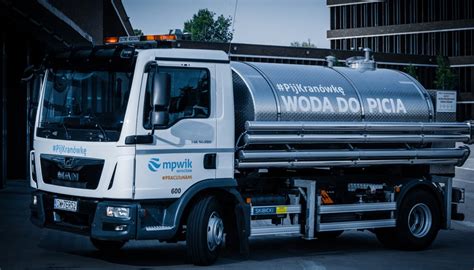 Tematyczne zdjęcie beczkowozu z logo MPWiK, rozdającego wodę mieszkańcom w upalny dzień