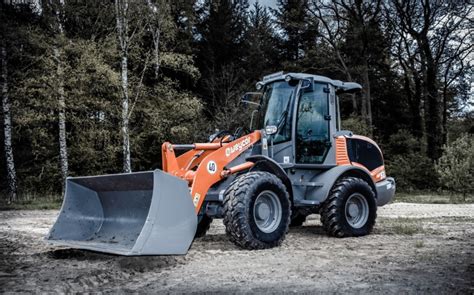 Zdjęcie przedstawiające nową ładowarkę przegubową Bobcat L85 na tle zakładu produkcyjnego w Dobříš.