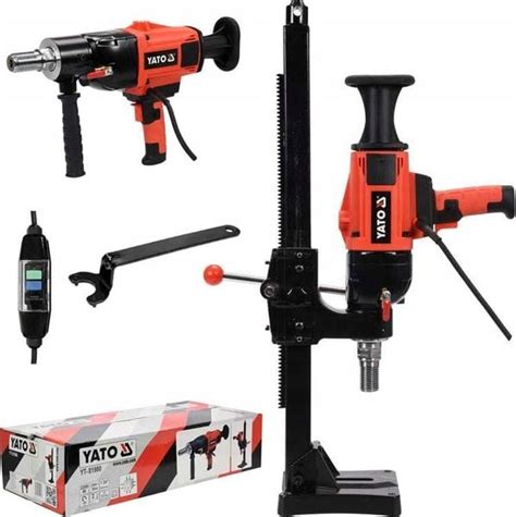 Zdjęcie przedstawiające wiertnicę diamentową YATO zamontowaną na statywie, w trakcie pracy w betonie