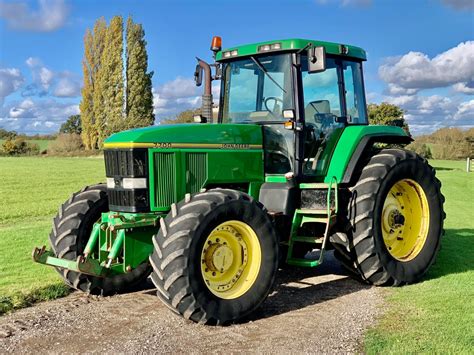 Zdjęcie ciągnika John Deere 7700 ciągnącego niskopodwoziówkę