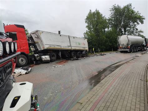 schemat miejsca wypadku z udziałem dwóch ciężarówek, z zaznaczeniem płonącego pojazdu, uszkodzonego ogrodzenia i wypadających pojemników z chemikaliami