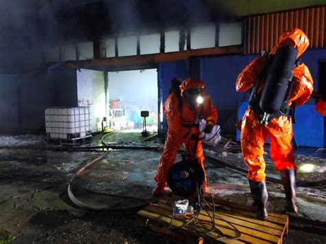 fotografia przedstawiająca strażaków zabezpieczających pojemniki z chemikaliami po wypadku drogowym