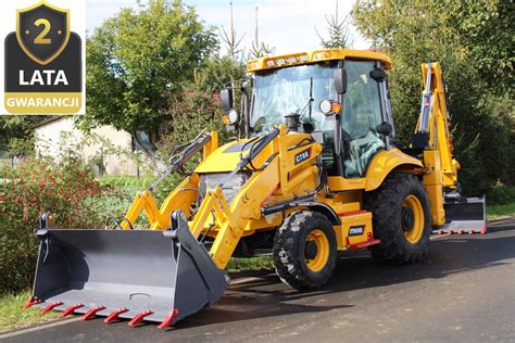 koparko-ładowarka w trakcie prac ziemnych, w tle widok na małe miasteczko lub wieś w Polsce