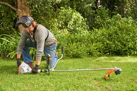 zdjęcie kosy spalinowej Stihl FS 55 w akcji, pokazujące ergonomiczny uchwyt oburęczny i pas nośny