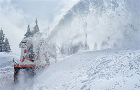 Thematic photo of a snow-covered road and a snow blower in action