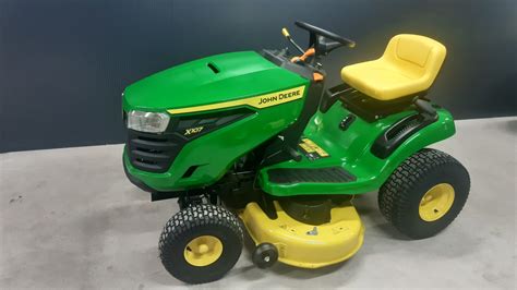 Widok ogólny traktorka ogrodowego John Deere X107 na zadbanym trawniku, prezentujący jego charakterystyczną zielono-żółtą stylistykę i agregat koszący Edge 42