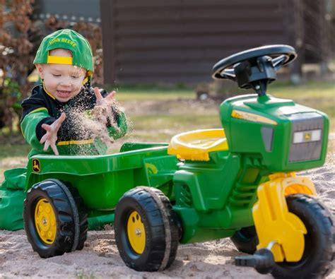 Traktor Rolly Kid John Deere z przyczepą, z widoczną kierownicą z dźwiękami
