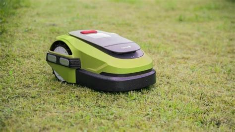 robot koszący pracujący w ogrodzie, z widoczną stacją dokującą