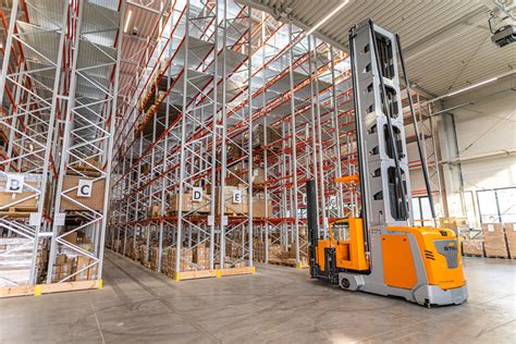 zdjęcie nowoczesnego magazynu logistycznego z operatorami wózków widłowych