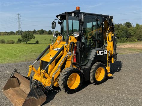 The JCB 1CX compact backhoe loader working in a confined space, illustrating its maneuverability and size.
