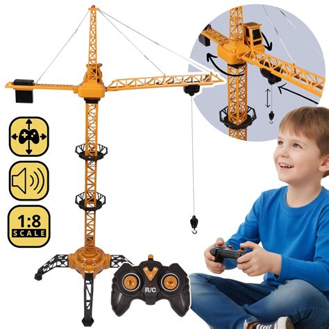 Zdjęcie przedstawiające zdalnie sterowany dźwig budowlany w akcji, z widocznym pilotem sterowania.