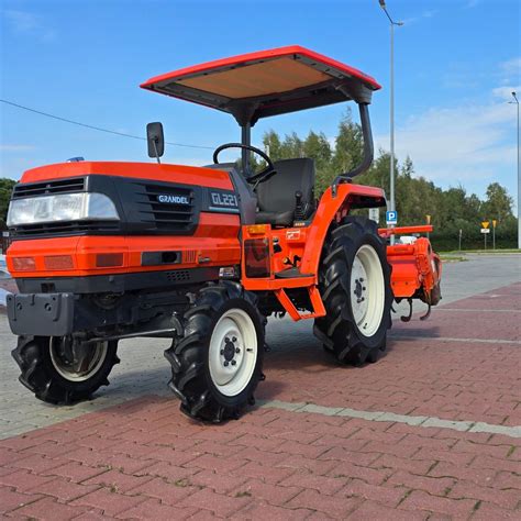 The Kubota Grandel GL221 tractor working with a rotary tiller in a field.