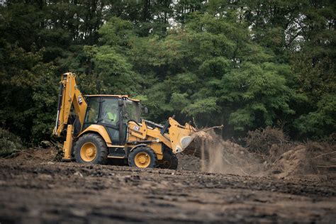 Thematic photo of a Caterpillar backhoe loader working in an urban environment or on landscaping tasks