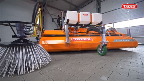 Ilustracja przedstawiająca ładowarkę JCB z zamontowaną zamiatarką Talex ECO CLEAN na terenie obiektu przemysłowego