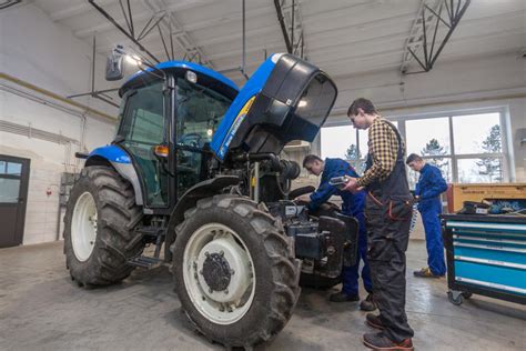 Mechanik serwisujący ciągnik rolniczy w warsztacie.