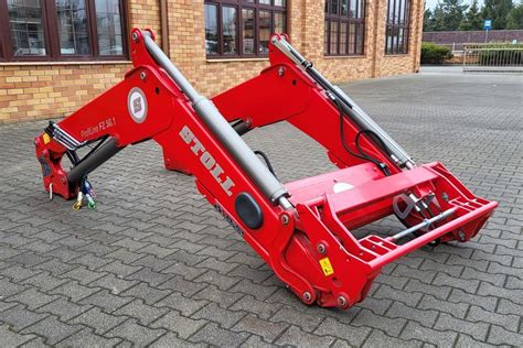 Tematyczne zdjęcie ładowacza czołowego Stoll z ciągnikiem w akcji na polu