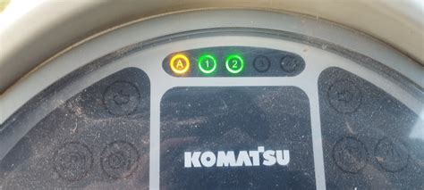 Panel sterowania koparki Komatsu z podświetlonymi przyciskami
