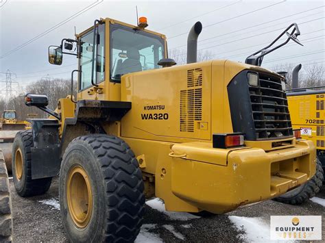 Photo of Komatsu WA320 equipped with pallet forks, working in a warehouse or on a construction site.