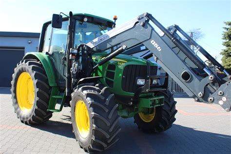 Ciągnik John Deere z zamontowanym ładowaczem czołowym Quicke podczas pracy