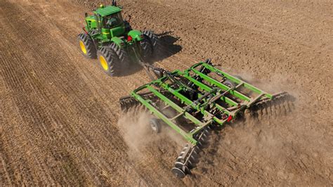 Tractor with a tiller attached, working on a large field