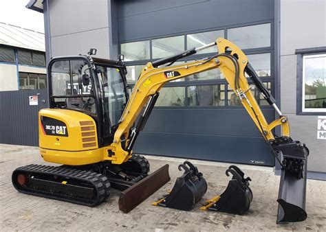 Minikoparka Cat z różnymi rodzajami osprzętu roboczego na placu budowy
