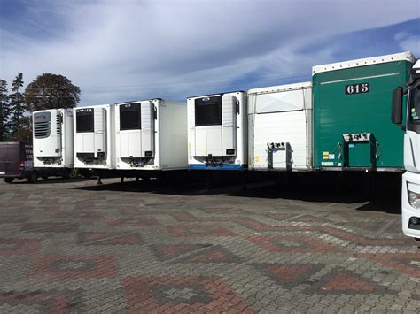 Zdjęcie przedstawiające różne typy naczep podłączone do ciągników siodłowych (np. chłodnia, wywrotka, platforma).