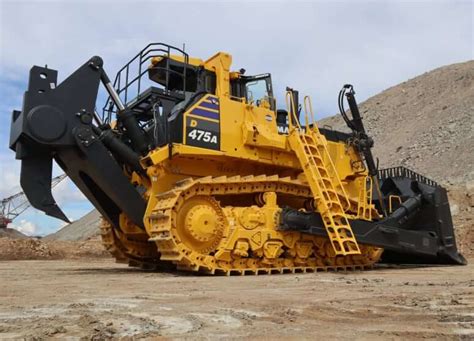 Rysunek techniczny Komatsu D475A z zaznaczonymi głównymi komponentami: silnikiem, układem napędowym, lemieszem i kabiną operatora.