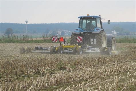 Zdjęcie bron talerzowych w akcji na polu, demonstrujące mulczowanie i mieszanie resztek roślinnych.