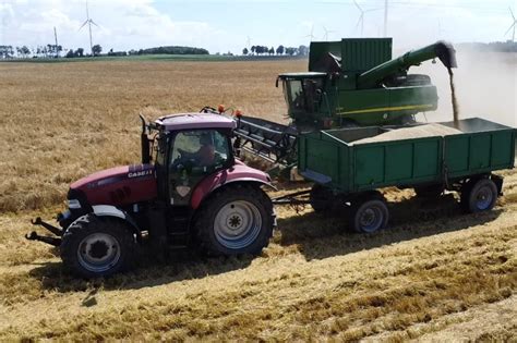 Wizualizacja kombajnu zbożowego podczas rozładunku ziarna do przyczepy, z widoczną długą rurą wysypową