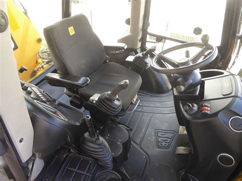 Wnętrze kabiny JCB 3CX z widocznymi joystickami i fotelem operatora