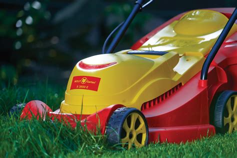 kosiarki elektryczne Wolf-Garten w różnych rozmiarach na tle zielonego ogrodu