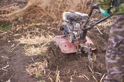 Thematic photo of a person operating a petrol tiller in a garden