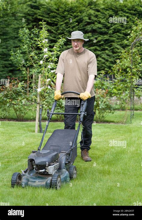 Thematic photo of a person pushing a petrol lawn mower in a small garden