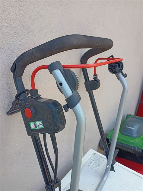 Zilustrowanie kosiarki elektrycznej w akcji, ze źródłem zasilania kablowym lub akumulatorowym