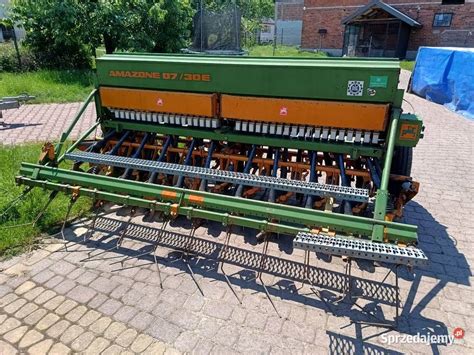 Rolnik sprawdzający używany siewnik zbożowy przed zakupem