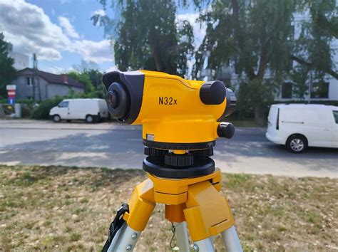 Niwelator na trójnożnym statywie w trakcie pracy