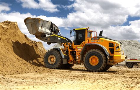 Thematic photo of a Lamborghini tractor with a front loader, working on a paved area or road, possibly pushing snow or moving pallets.